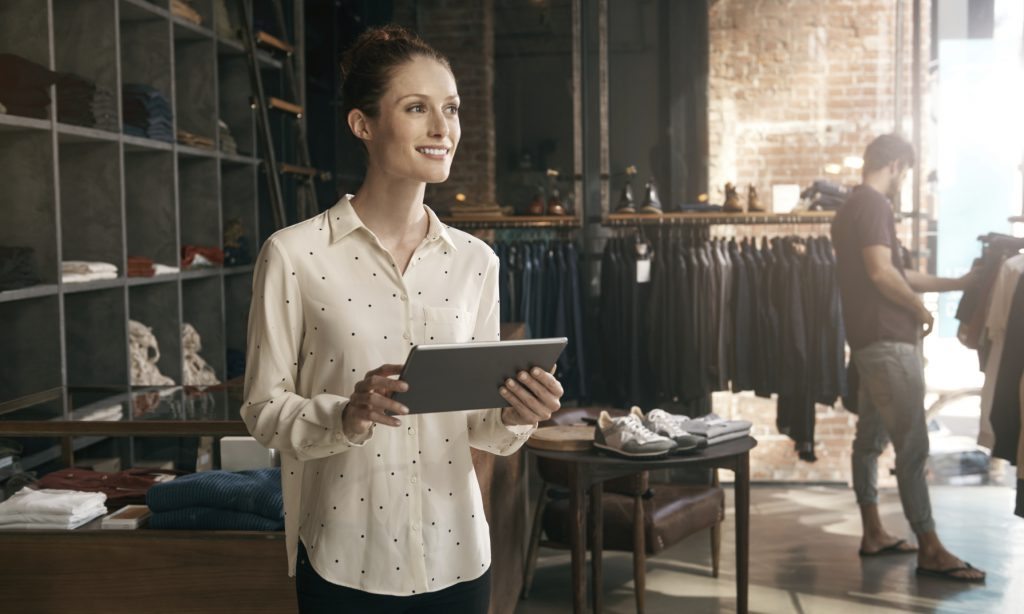 Best Credit Card Processing Company - woman holding a tablet smiling in a men's clothing store