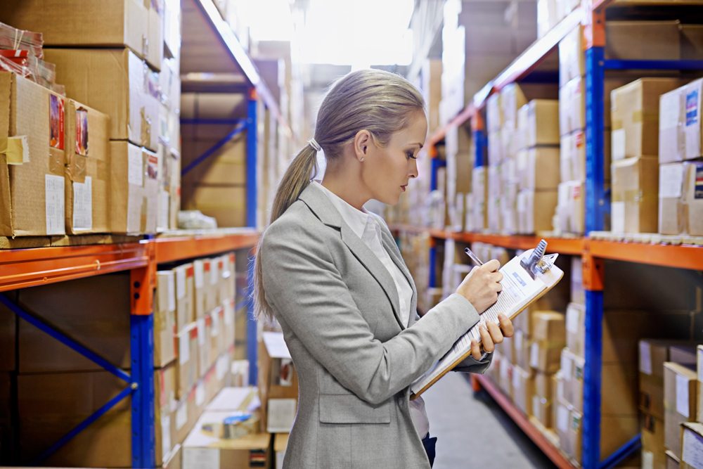 Inventory Control Software - woman in a large warehouse tracking inventory