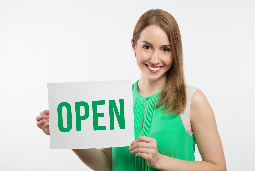 Payment Service Provider - woman in a green dress smiling and holding an OPEN sign