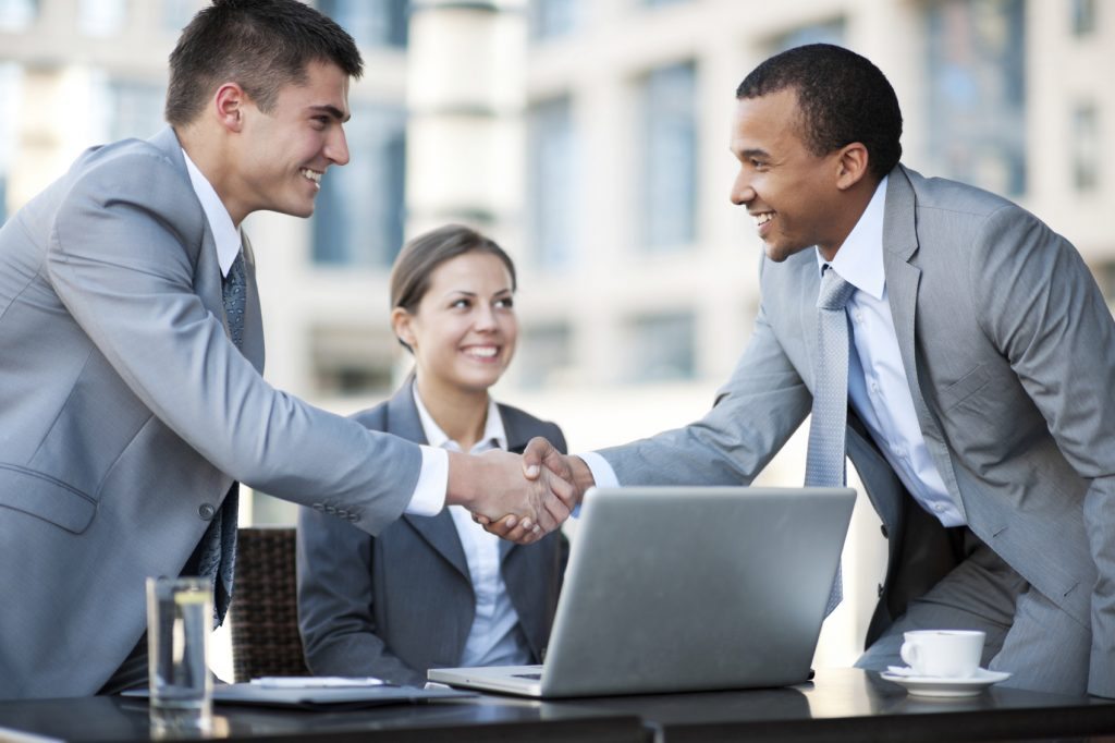 Affinity Partners - two business men shaking hands with a woman smiling behind them