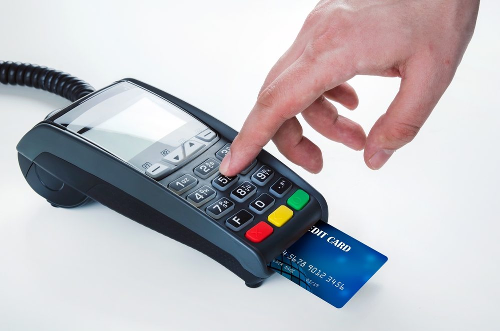 EMV - man pressing a small credit card terminal button with credit card sticking out